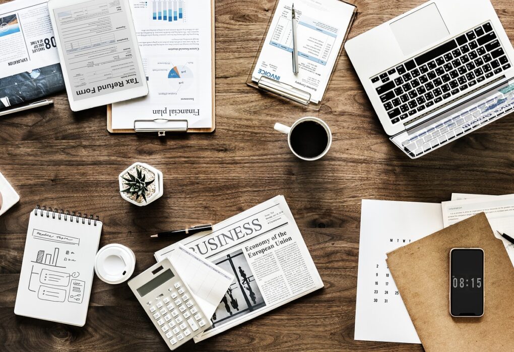 A messy table with a laptop and financial documents for planning to spend money wisely.