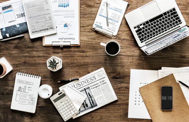 A messy table with a laptop and financial documents for planning to spend money wisely.
